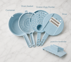 A set of light blue kitchen utensils labeled with callouts: Container, Drain basket, Grater+Egg Divider, Slicer, and protective handholder, arranged on a white marble surface.