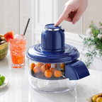 A blue countertop food chopper with a clear bowl filled with orange fruits, shown on a kitchen counter with a hand pressing the top button. A drink and other kitchen items are blurred in the background.