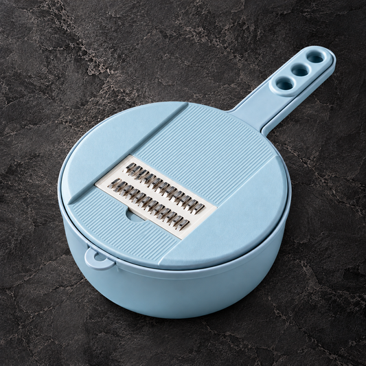 A light blue plastic mandoline slicer with a handle and three finger holes, resting on a dark textured stone surface.