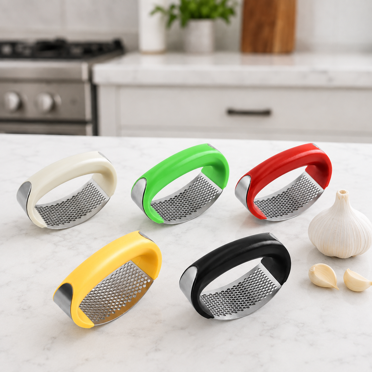 Five garlic press tools in cream, green, red, yellow, and black are arranged on a white marble countertop with garlic cloves and a whole garlic bulb nearby, and a blurred kitchen background.